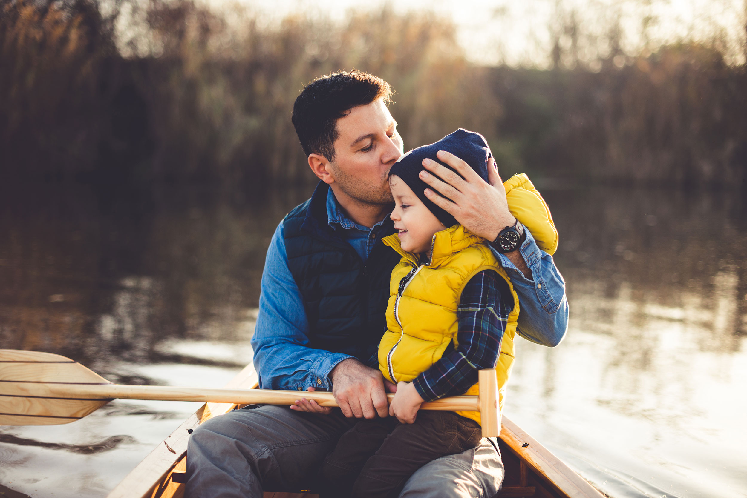 homme père embrassant son films sur une barque sur un lac week-end famille