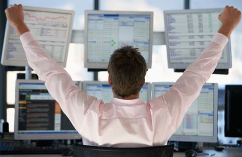 courtier devant six écran devant la bourse levant les bras en l