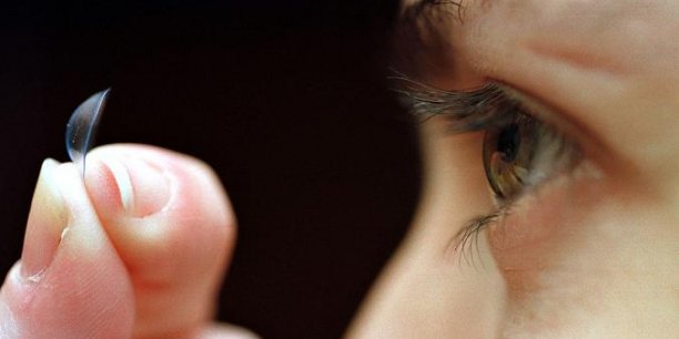 femme mettant ses lentilles avec ses doigts dans ses yeux sur fond noir
