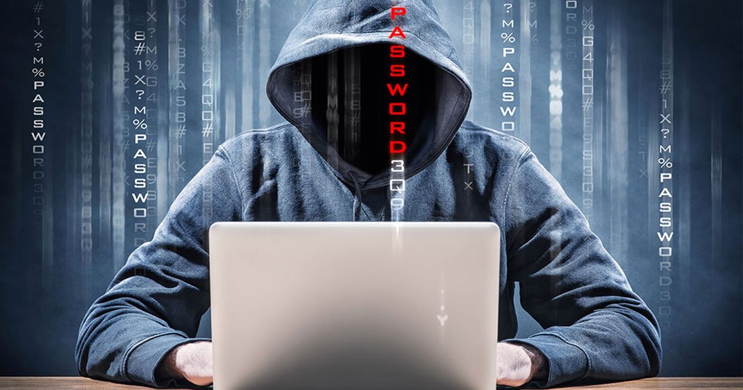 informaticien hackeur derriere son ordinateur avec capuche visage noir